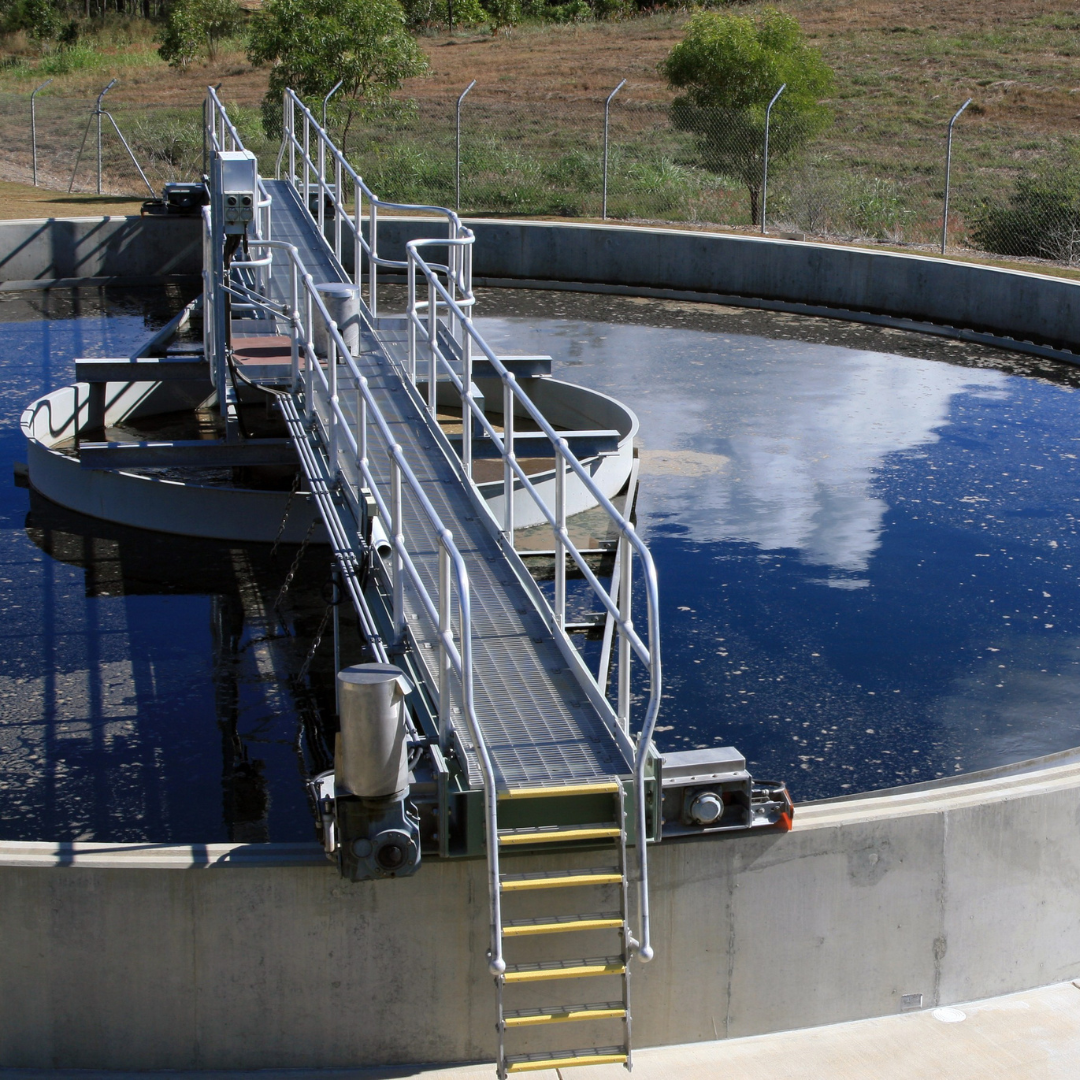 An aerial view of a water treatment plant with a circular tank and a walkway over the surface.