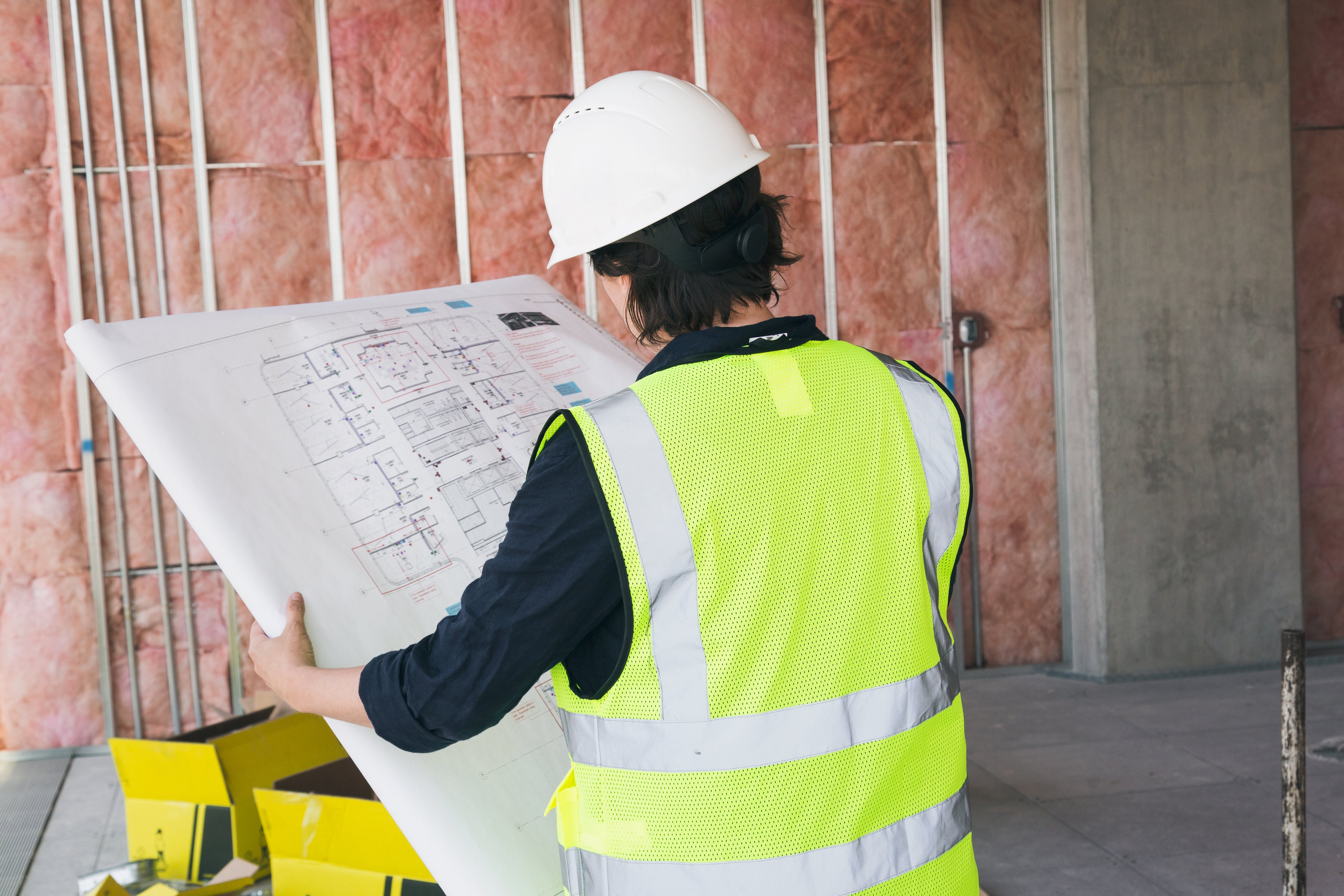A construction worker in a protective hat, holding blueprints.