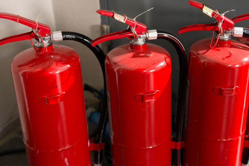 Three red fire extinguishers standing in a row