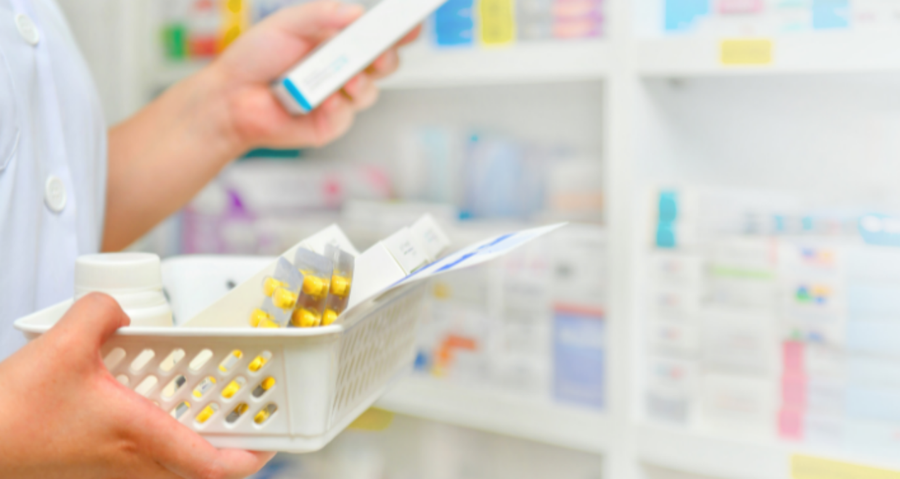 A pharmacist filling a prescription while holding a tray 